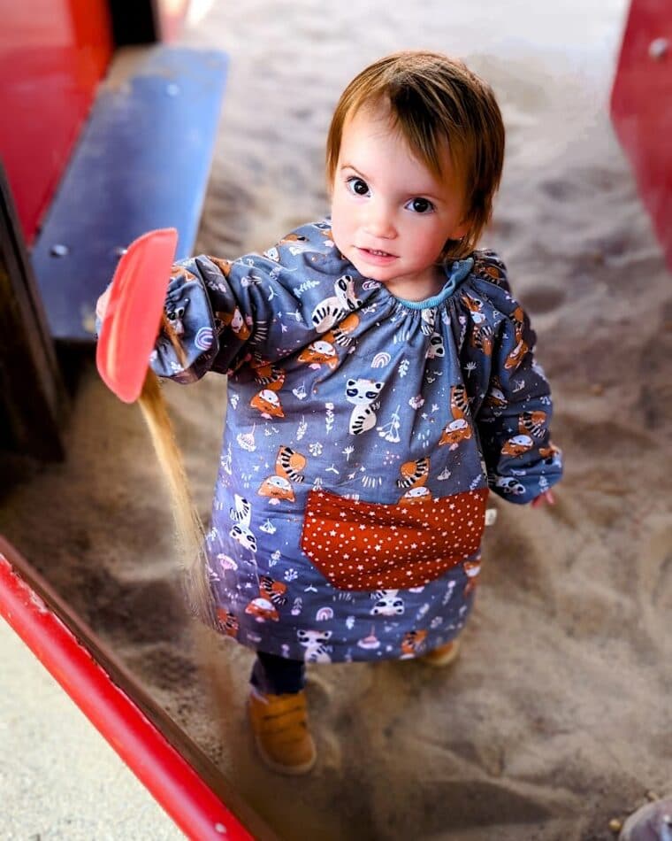 Niño pequeño con bata de estampado espacial y bolsillo naranja