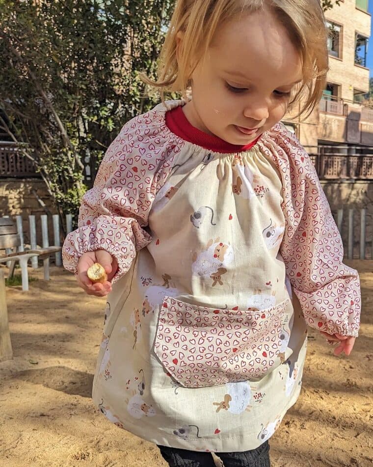 Niña con bata escolar de flores en el patio