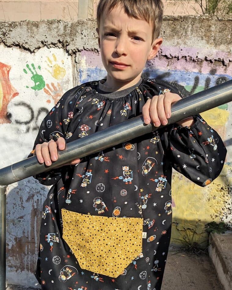 Niño con bata oscura estampada y bolsillo amarillo