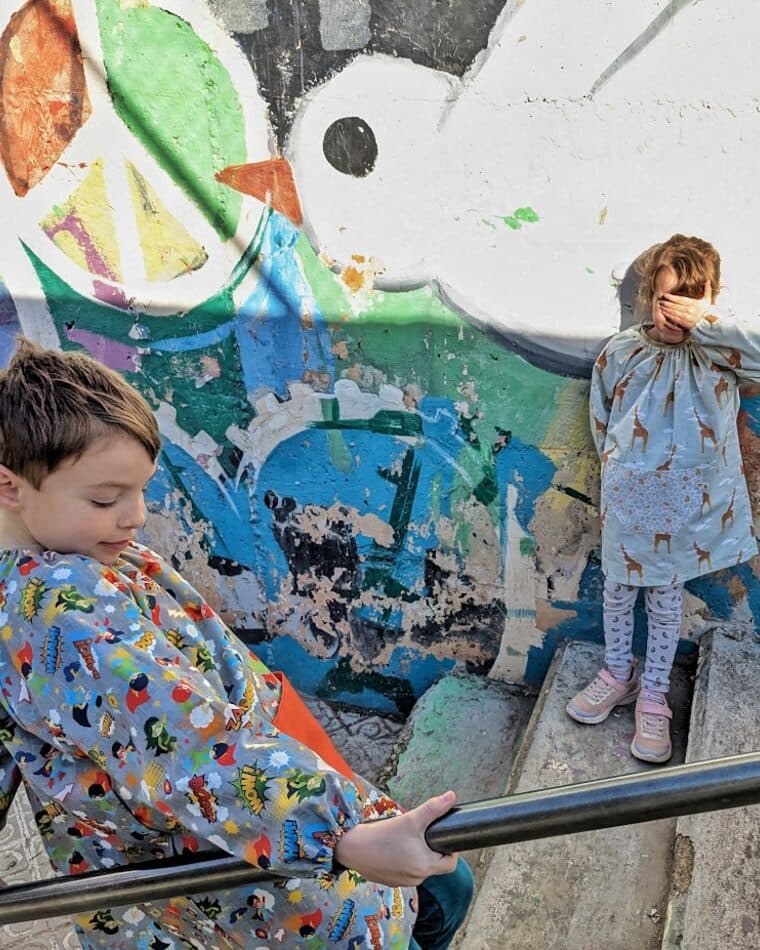 Niño con bata delante de un mural pintado