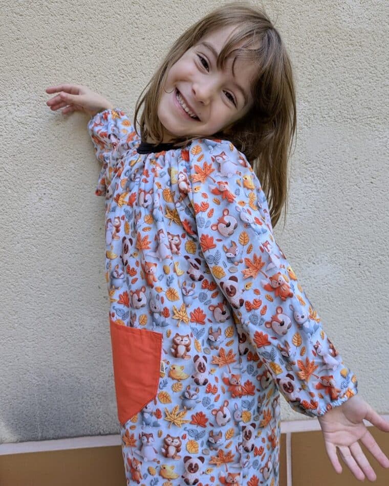 Niña con bata de flores azules y bolsillo rosa