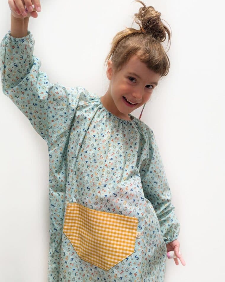 Niña con bata de flores en tono menta y bolsillo amarillo