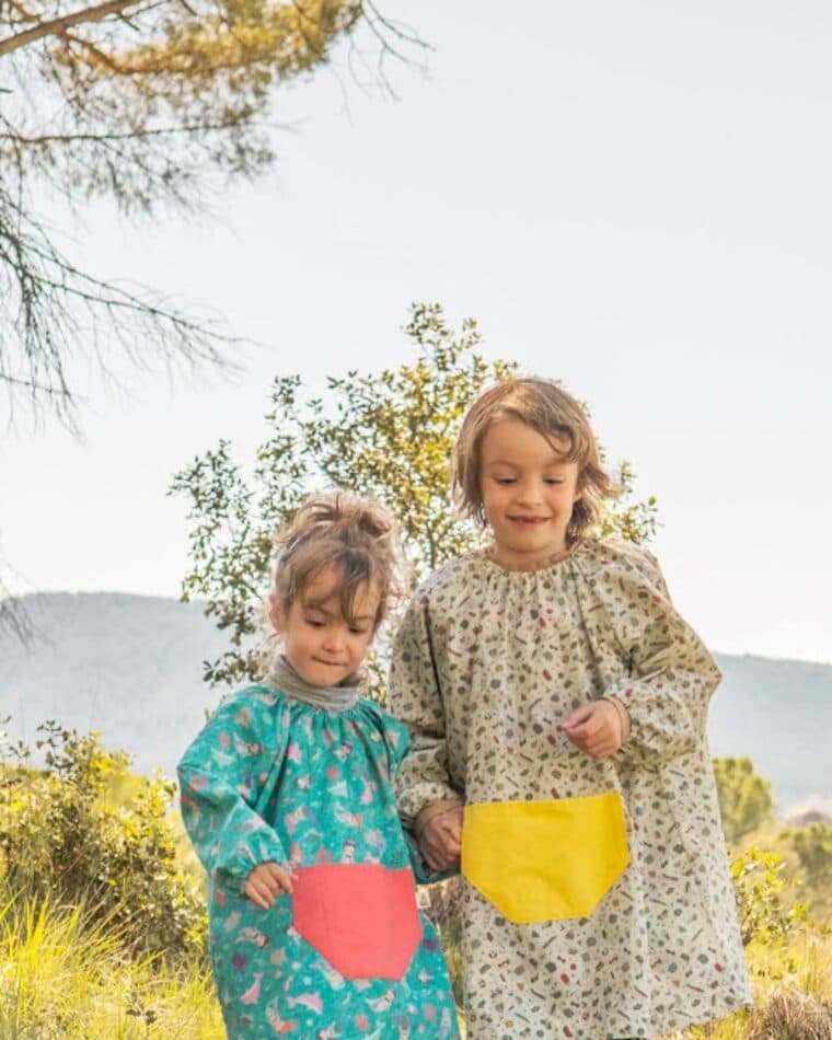 Dos niñas con bata escolar en un camino del bosque