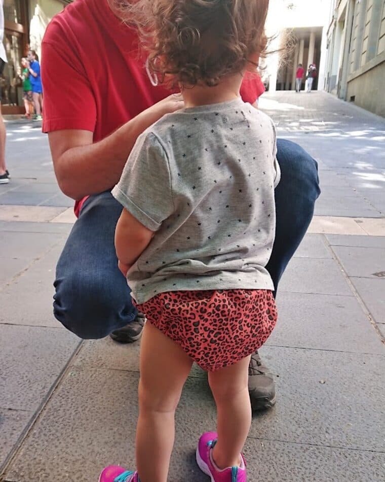 Cubrepañal de estampado rojo puesto a un bebé que empieza a andar